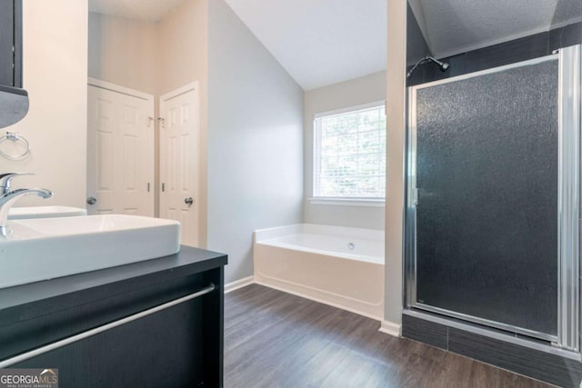 full bath featuring double vanity, a shower stall, a bath, and wood finished floors