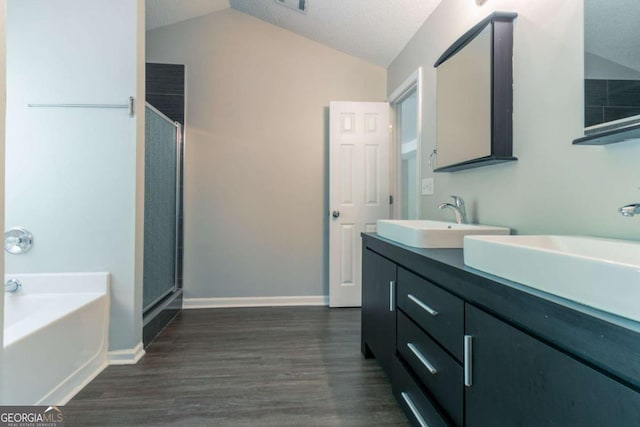 full bathroom featuring a sink, vaulted ceiling, a stall shower, and wood finished floors