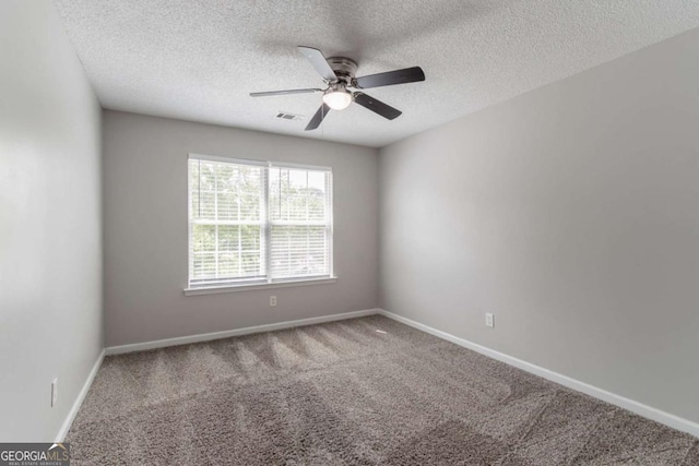 carpeted empty room with a textured ceiling, baseboards, a ceiling fan, and visible vents