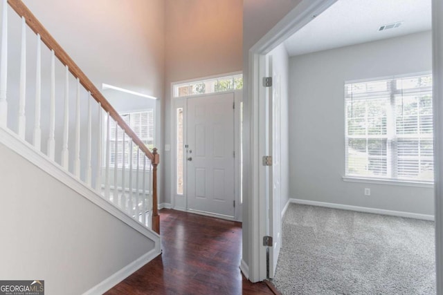 foyer entrance with stairs, baseboards, visible vents, and wood finished floors