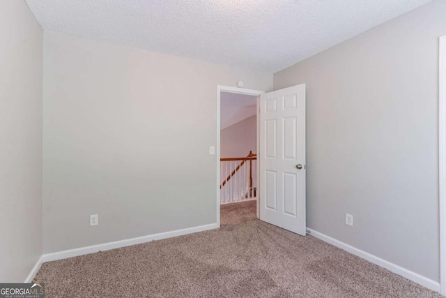 carpeted spare room with baseboards and a textured ceiling