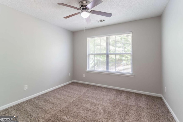 spare room with a textured ceiling, baseboards, and carpet