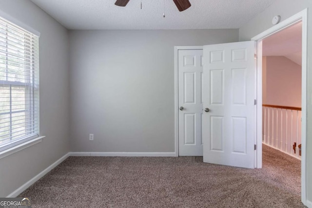unfurnished bedroom featuring multiple windows, carpet flooring, and a textured ceiling
