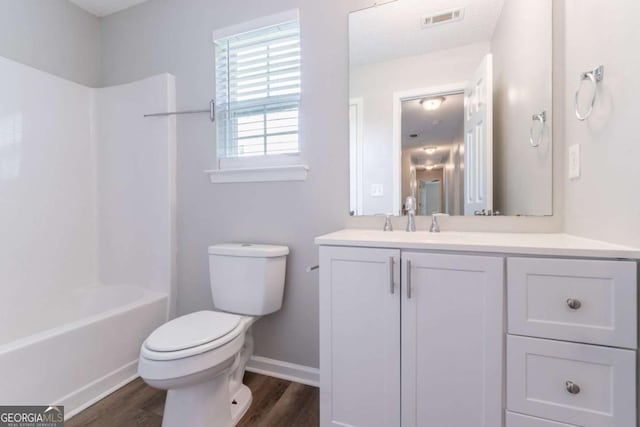 full bathroom with toilet, baseboards, visible vents, vanity, and wood finished floors