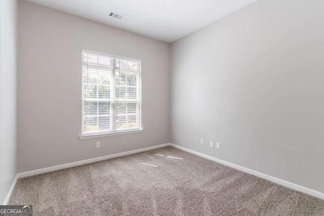 spare room with carpet, visible vents, and baseboards
