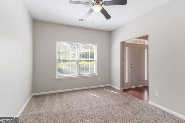 carpeted empty room with baseboards, visible vents, and ceiling fan
