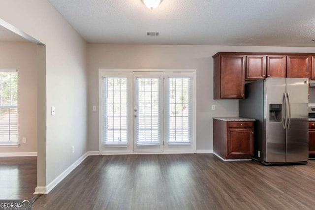kitchen with a textured ceiling, dark wood-type flooring, baseboards, visible vents, and stainless steel fridge with ice dispenser