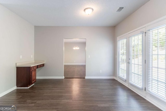 unfurnished room featuring a chandelier, visible vents, baseboards, and dark wood-style floors