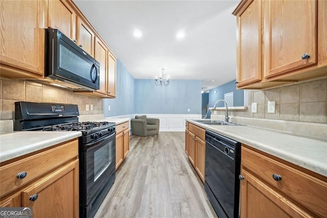 kitchen featuring tasteful backsplash, light wood-type flooring, a sink, black appliances, and a chandelier
