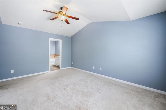 unfurnished bedroom featuring baseboards, ensuite bathroom, carpet, and lofted ceiling