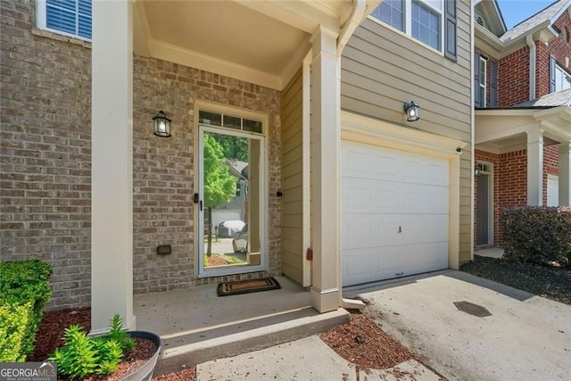 entrance to property featuring brick siding, driveway, and a garage