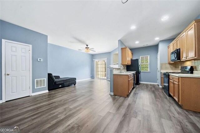 kitchen featuring visible vents, a sink, dark wood-type flooring, and black appliances