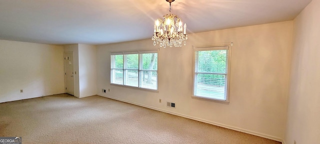 carpeted empty room featuring visible vents, baseboards, and a notable chandelier