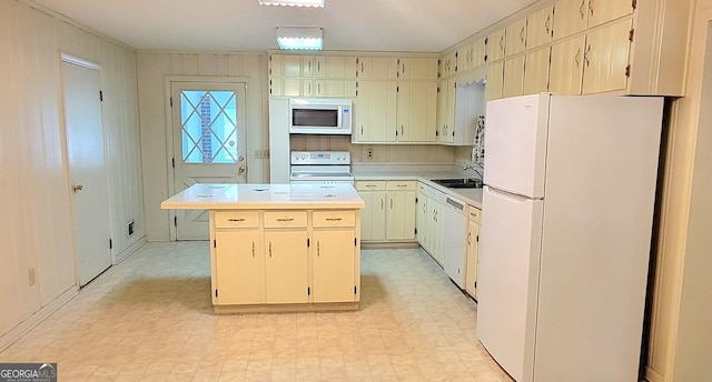 kitchen with light floors, light countertops, a sink, and white appliances