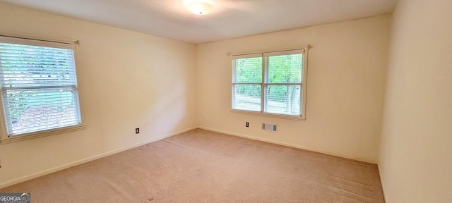 spare room featuring baseboards, visible vents, and light colored carpet