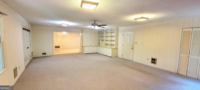 unfurnished room with ceiling fan, light carpet, wood walls, and a textured ceiling