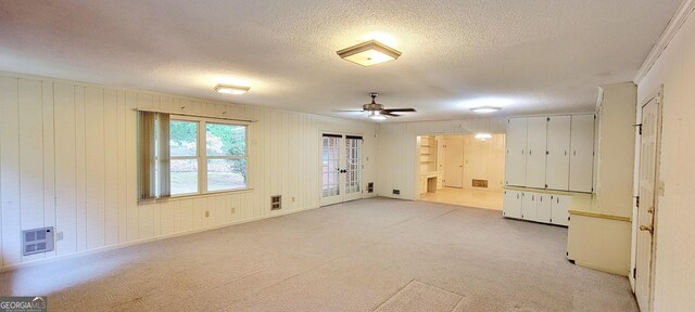 unfurnished room featuring light carpet, a ceiling fan, and a textured ceiling
