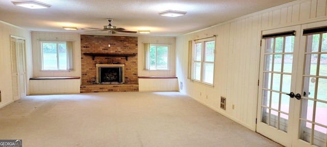 unfurnished living room featuring a healthy amount of sunlight, crown molding, a fireplace, carpet flooring, and ceiling fan