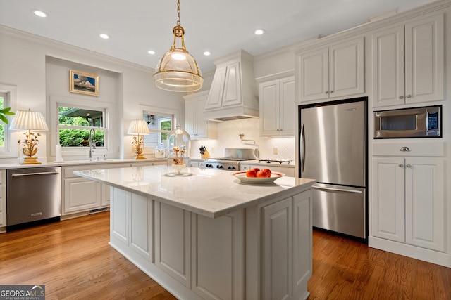 295 Goble Gap Rd, Clayton, GA 30525 - kitchen featuring appliances with stainless steel finishes, custom exhaust hood, a kitchen island, light wood-style flooring, and decorative backsplash