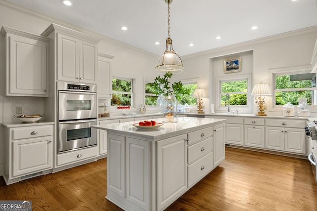 295 Goble Gap Rd, Clayton, GA 30525 - kitchen featuring stainless steel double oven, healthy amount of natural light, a kitchen island, ornamental molding, and decorative backsplash