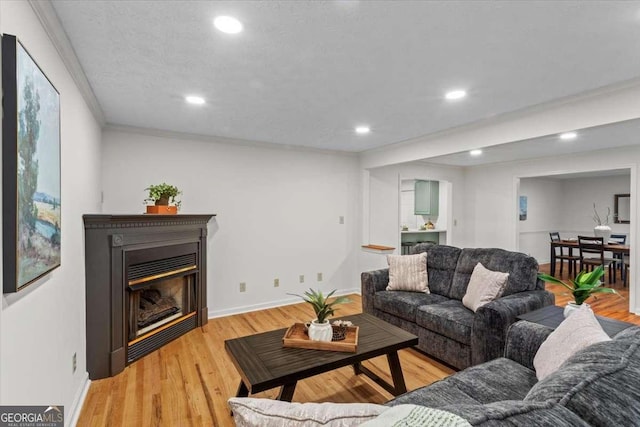5766 Macland Rd, Powder Springs, GA 30127 - living room featuring recessed lighting, a glass covered fireplace, crown molding, and light wood-type flooring