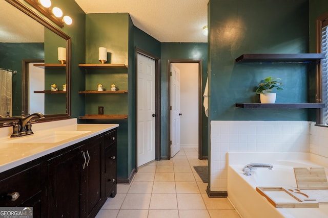 full bath featuring tile patterned floors, a textured ceiling, vanity, baseboards, and a garden tub