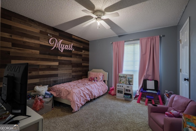 bedroom featuring a ceiling fan, wooden walls, a textured ceiling, and carpet flooring