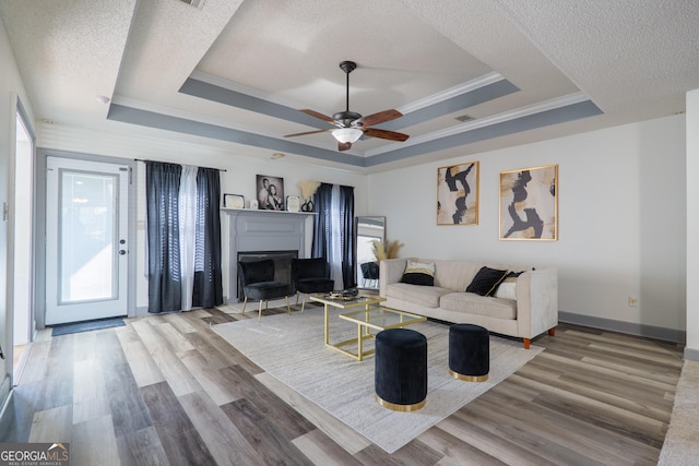 living area with a textured ceiling, a healthy amount of sunlight, and a tray ceiling