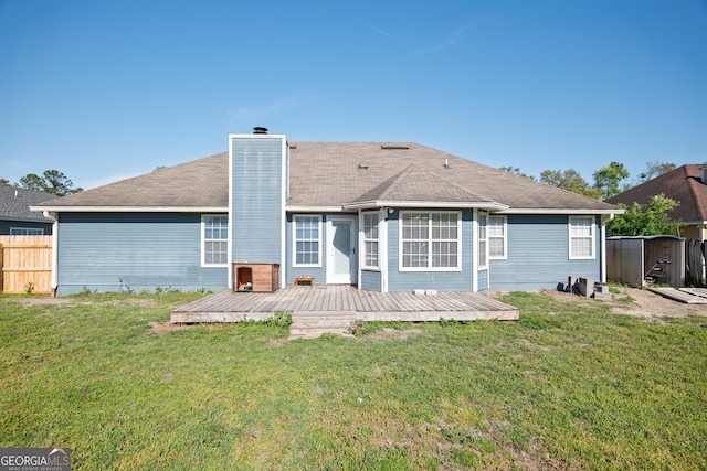 back of house featuring fence, a yard, a wooden deck, and a chimney