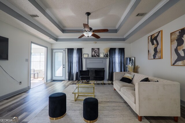 living area featuring a textured ceiling, wood finished floors, a ceiling fan, and a tray ceiling