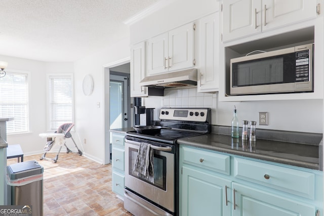 kitchen with white cabinets, appliances with stainless steel finishes, under cabinet range hood, and tasteful backsplash