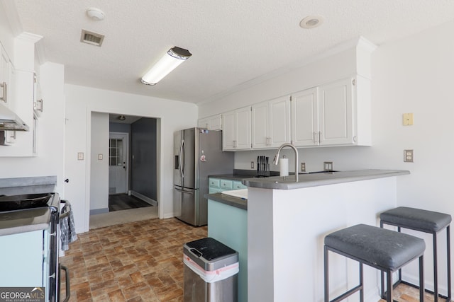 kitchen with white cabinetry, appliances with stainless steel finishes, visible vents, a kitchen bar, and a peninsula