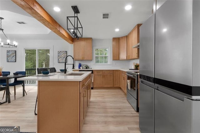 kitchen with a sink, a center island with sink, visible vents, light countertops, and appliances with stainless steel finishes