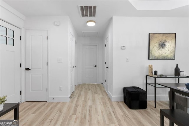 corridor with attic access, baseboards, light wood finished floors, and visible vents