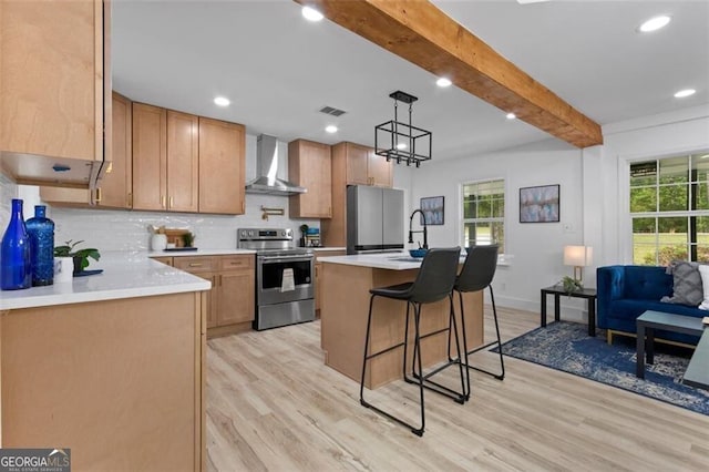kitchen with beamed ceiling, light wood-style flooring, wall chimney exhaust hood, and stainless steel appliances