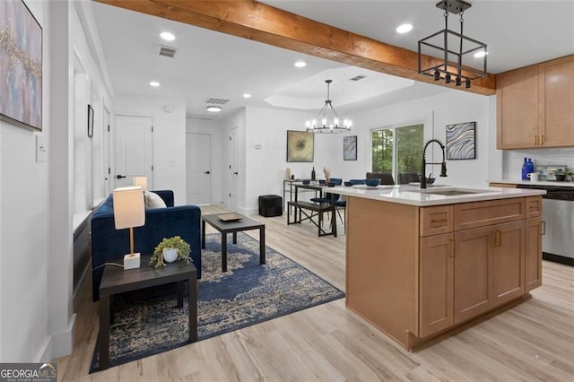 kitchen featuring light countertops, a sink, a center island with sink, a chandelier, and light wood-style flooring