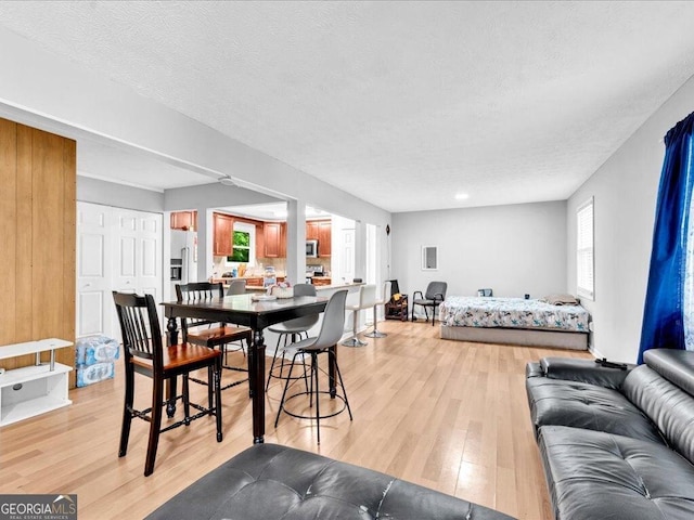 dining room with a textured ceiling, a healthy amount of sunlight, and light wood-type flooring