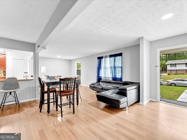 dining area featuring a textured ceiling, light wood finished floors, and baseboards