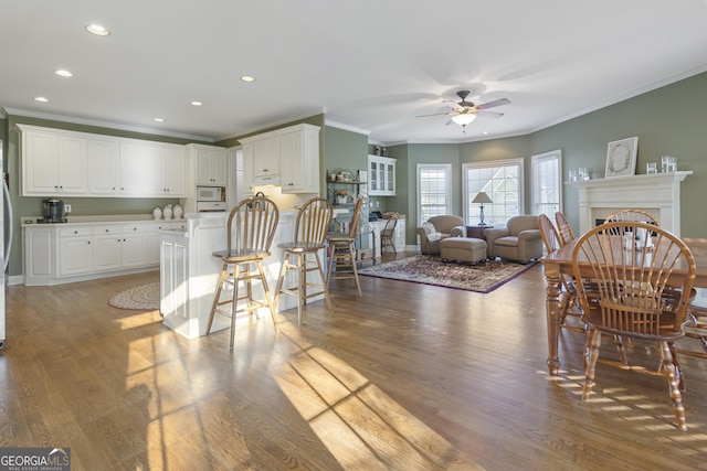dining room with a ceiling fan, wood finished floors, and crown molding