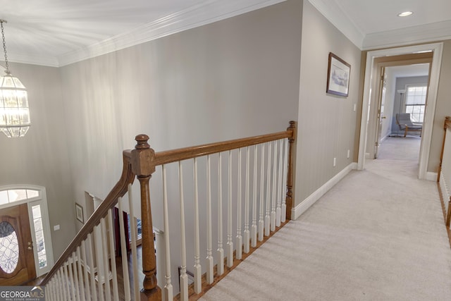 corridor featuring carpet, ornamental molding, a notable chandelier, and an upstairs landing