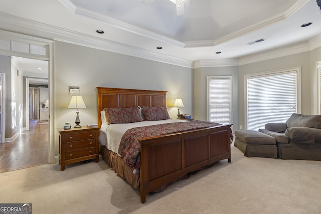 bedroom with a raised ceiling, visible vents, a ceiling fan, ornamental molding, and light colored carpet