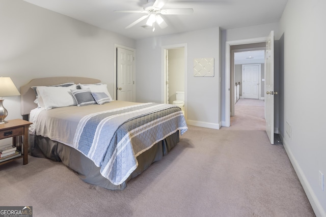 bedroom featuring ceiling fan, ensuite bath, baseboards, and light carpet