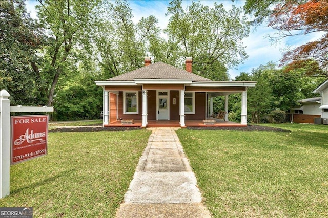 19 Mcdonough St, Hampton, GA 30228 - bungalow-style home with a chimney, a shingled roof, covered porch, and a front lawn