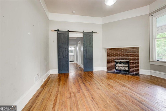 19 Mcdonough St, Hampton, GA 30228 - unfurnished living room with visible vents, a barn door, wood finished floors, and baseboards