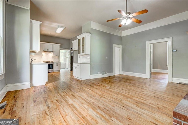 19 Mcdonough St, Hampton, GA 30228 - unfurnished living room with visible vents, ceiling fan, a sink, baseboards, and light wood-type flooring