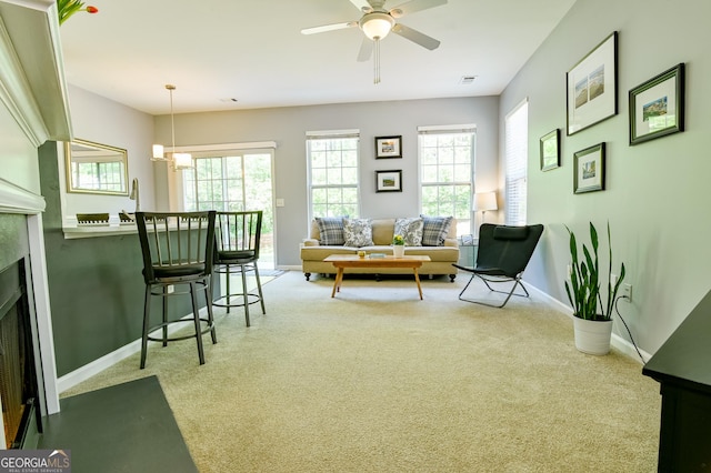 living area with a fireplace with flush hearth, carpet, baseboards, and ceiling fan