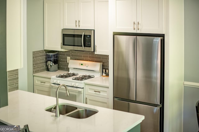 kitchen featuring decorative backsplash, appliances with stainless steel finishes, a sink, and white cabinets