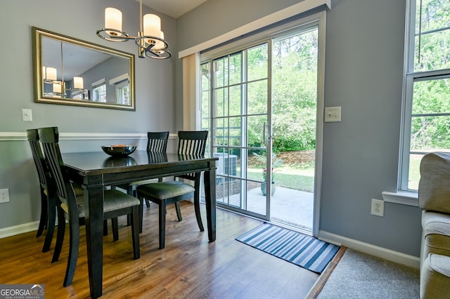 dining space featuring wood finished floors, baseboards, and an inviting chandelier