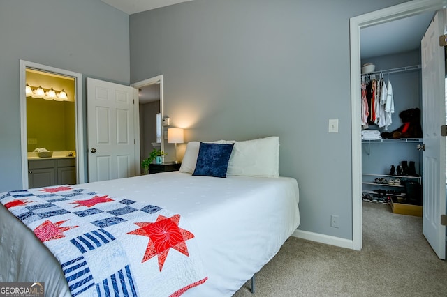carpeted bedroom featuring a walk in closet, a closet, baseboards, and ensuite bathroom