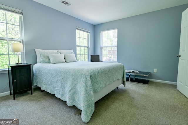 carpeted bedroom featuring visible vents, baseboards, and multiple windows